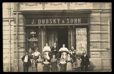 גלוית צילום ובה חזית בית המסחר J. Dubsky & Sohn בגמינד שבאוסטריה התחתית, ולפניה ניצבים בעלי 