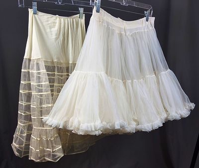 2 Vintage c1950s Petticoats. A white petticoat that is knee length. The waistband is slightly 