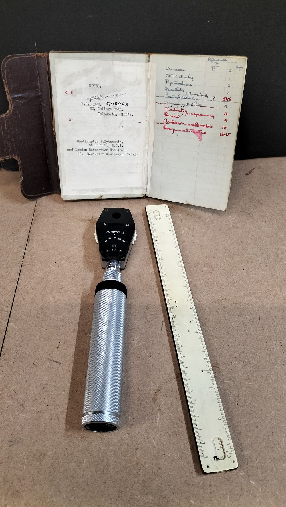 Lot 369: A Heine Autofoc 2 Ophthalmoscope with Medical Notebook and Slide Rule