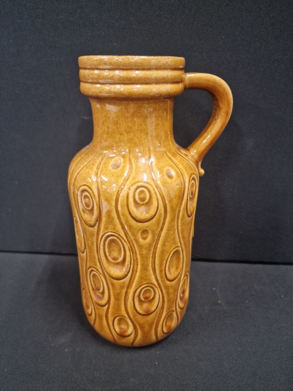 Lot 107: An unusual mustard West German vase with handle....