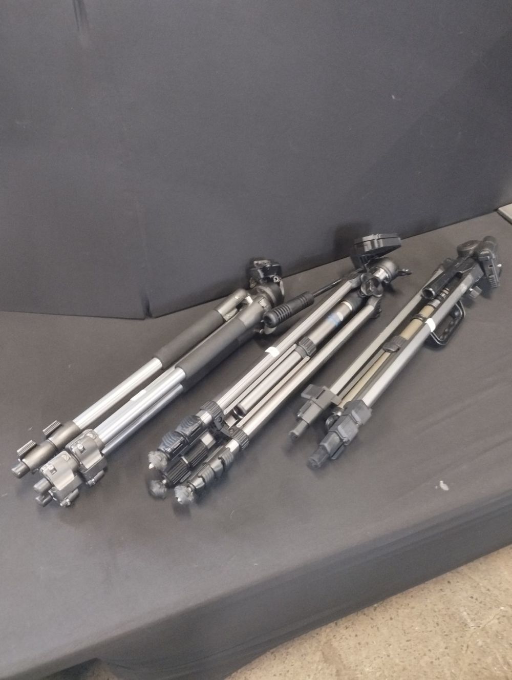 Lot 303: Three Professional Camera Tripods and a Selfie Stick.