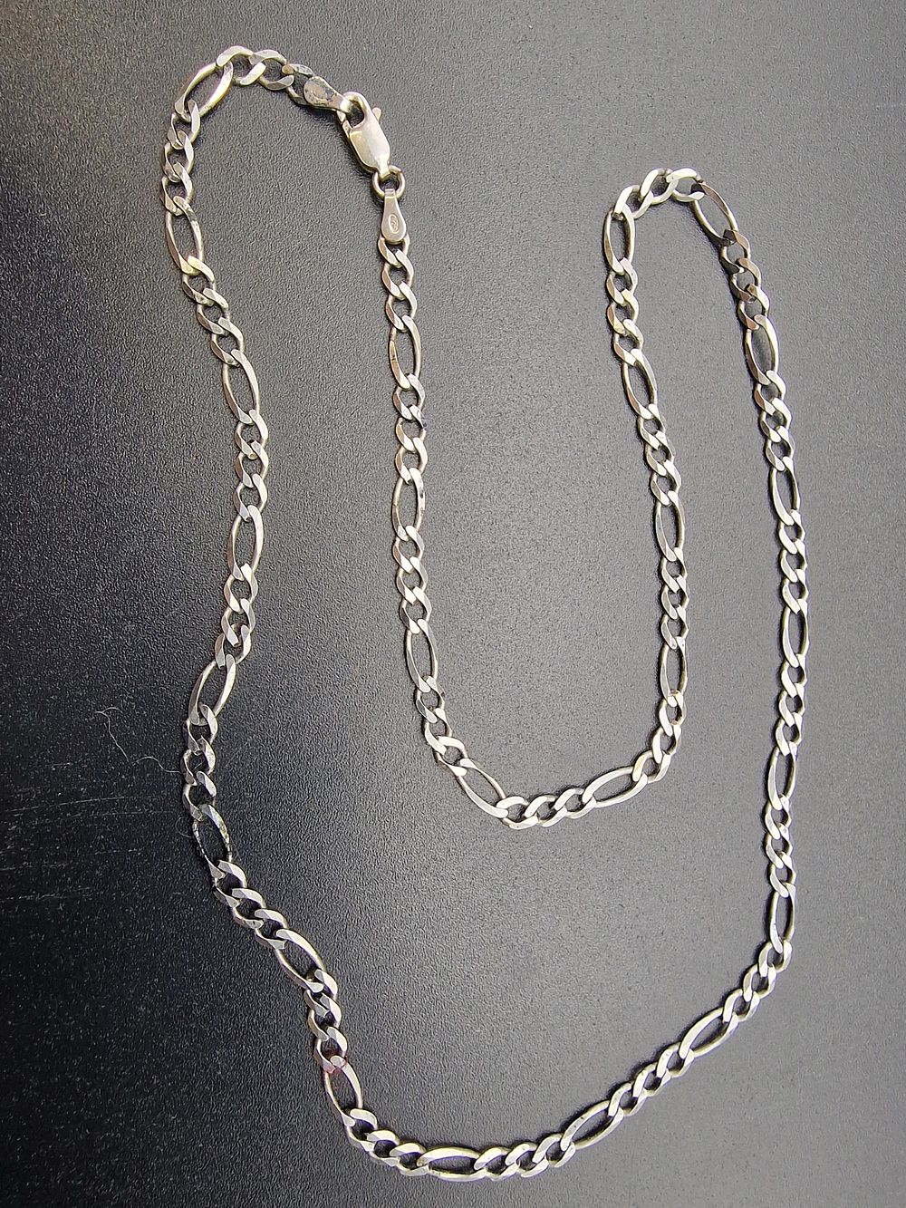 Lot 486: A unisex sterling silver figaro chain.