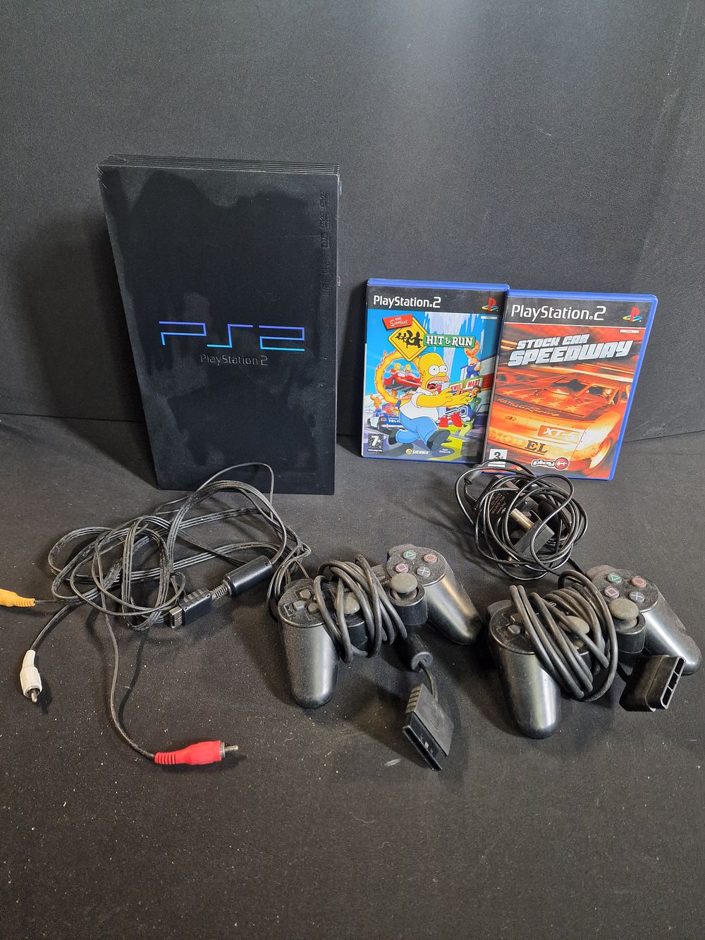 Lot 209: Vintage Sony PlayStation 2 Console. Includes 2 Games, 2 Controllers, HDMI/AV Leads. Dies not include Power Lead