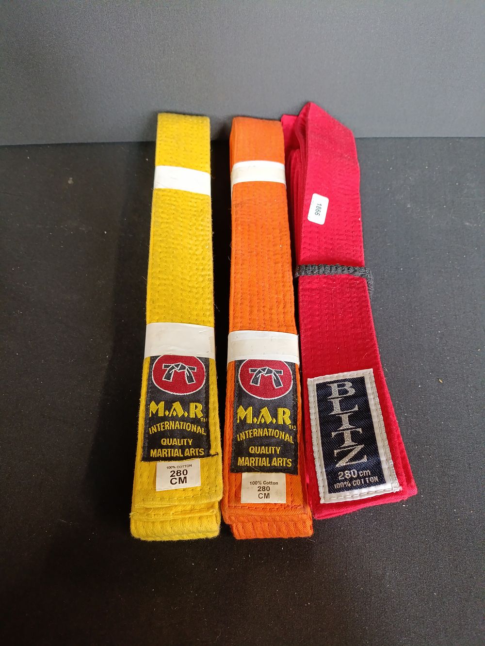 Lot 217: Three coloured martial arts belts, yellow, orange and...
