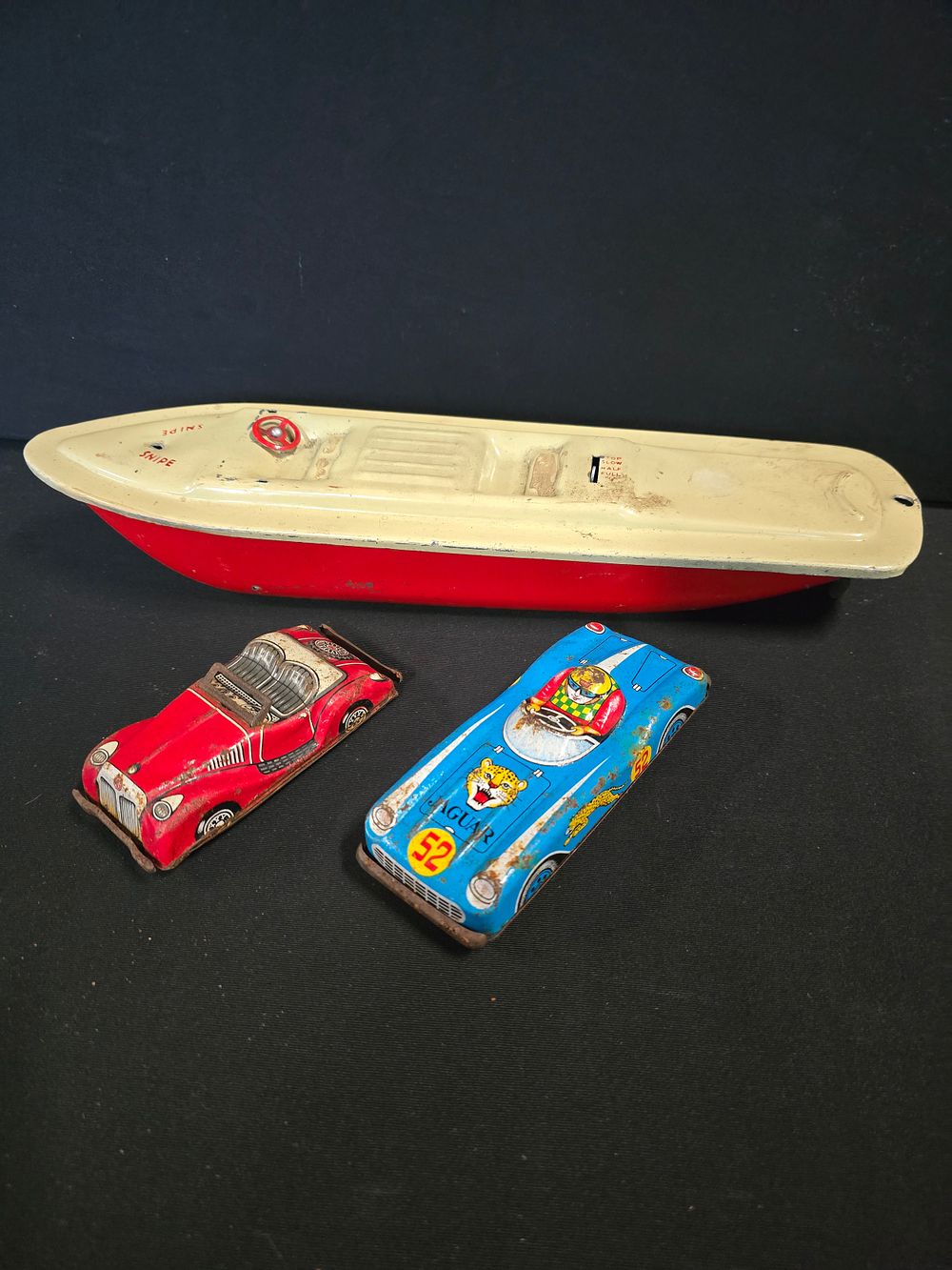 Lot 386: Three vintage tin cars and boat.