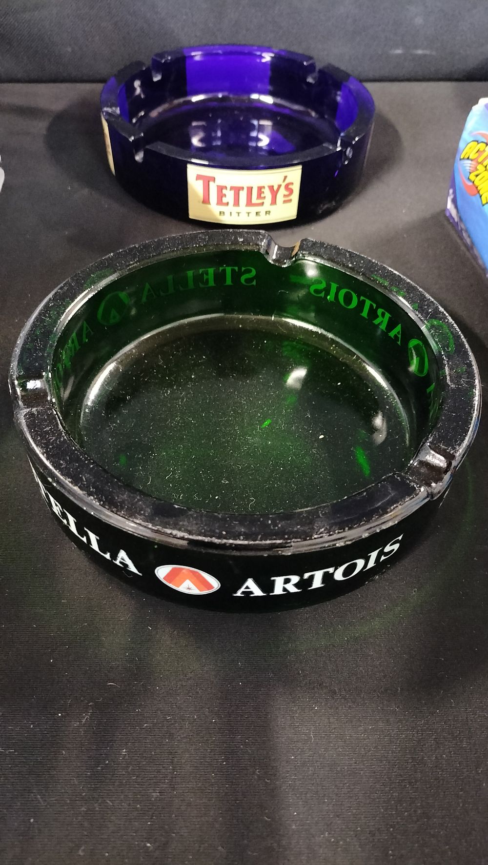 Lot 788: Two glass ashtrays. Green Stella Artois and blueTetley's...