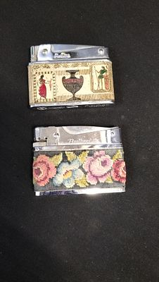 Two lighters one has a floral material and one has Egyptian enameling