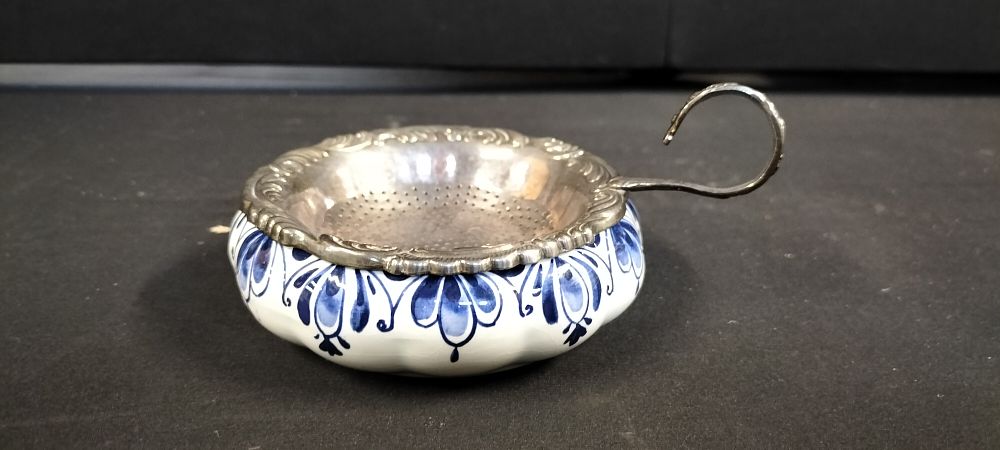 Lot 289: A Delft Blue Tea Strainer Set with a Silver Plated Strainer and Hand Painted Drip Tray
