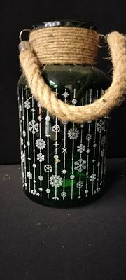 A Green Glass Christmas Lantern With a Snowflake Pattern and a Rope Handle