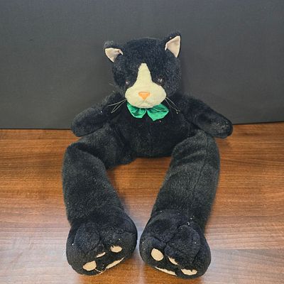 Black and White Long-Legged Plush Cat Toy with Green Bow Tie. A single black and white plush 