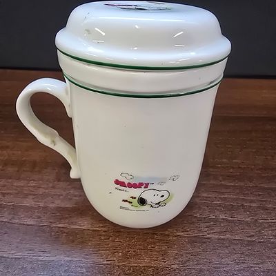 A Three-Piece Peanuts Snoopy Ceramic Infuser Mug Set by Everwin. A three-piece ceramic tea or 