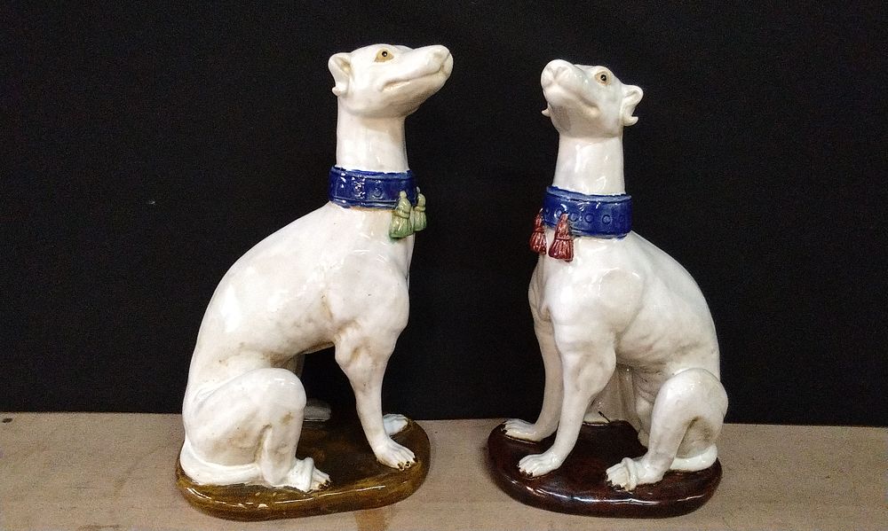Lot 183: A Pair of Mid-Century Italian Majolica Greyhounds. One Has Red Tassle on Blue Collar on a Dark Brown Base and One Has Green Tassle On Blue Collar on a light Brown Base.