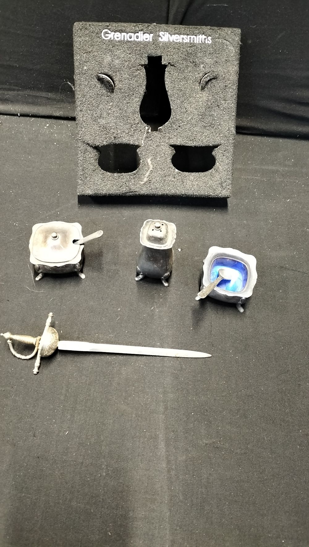 Lot 218: A Set of Silver Plated Salts with a Pepper Shaker and a Toledo Letter Opener