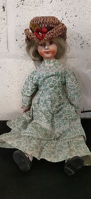 Porcelain doll with blonde hair and floral print dress. A porcelain doll featuring blonde hair 