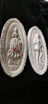 A Pair of Oval Bas-Relief Period Dress Wall Plaques. A pair of off-white oval-shaped decorative 