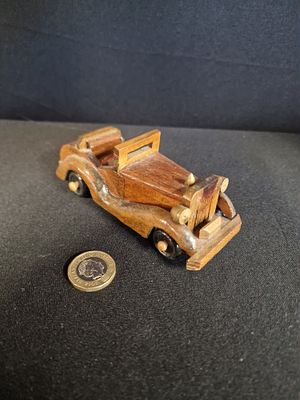 Handcrafted Wooden Model of a Vintage Car. A small brown-toned wooden model of a vintage car 