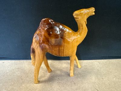 Hand Carved Wood Camel Figurine. A single hand carved wood camel figurine featuring a glossy 
