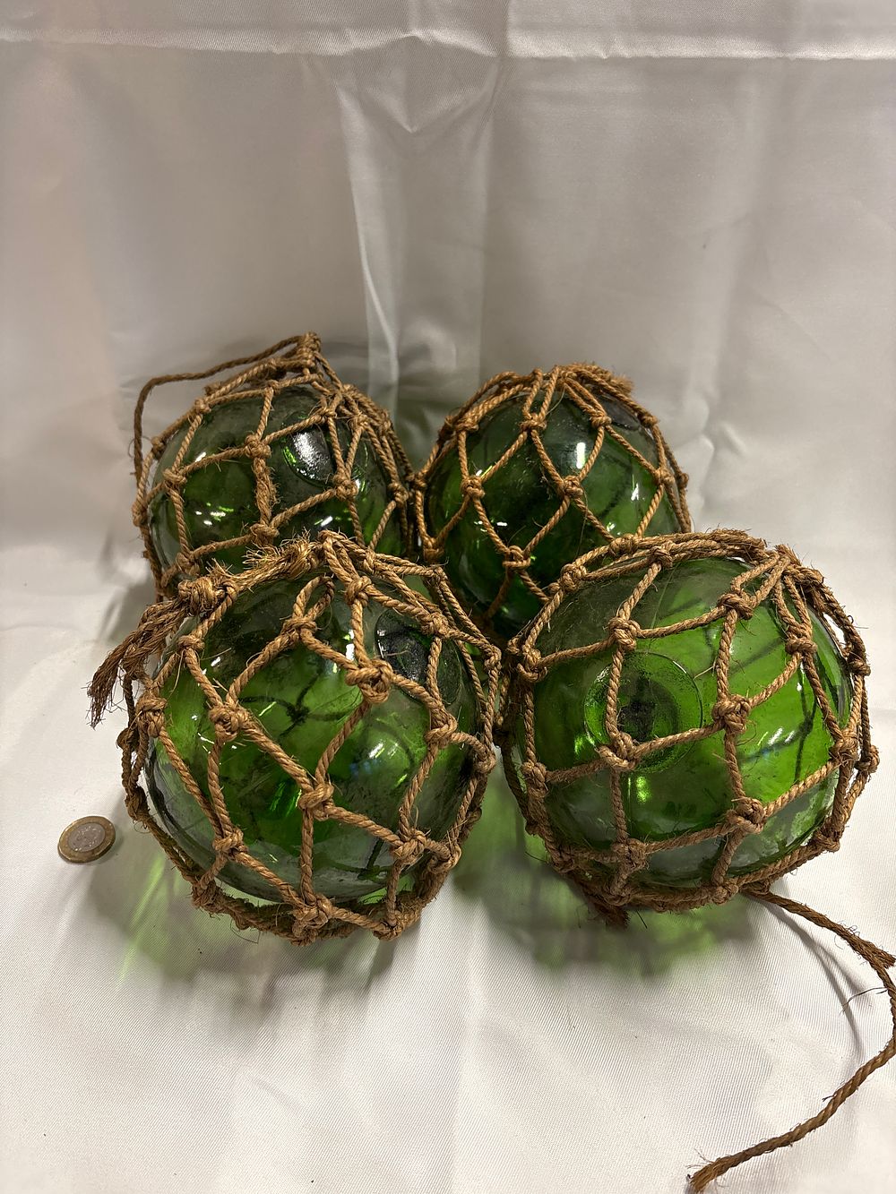 Lot 247: A Group of Four Vintage-Style Green Glass Fishing Floats in Rope Netting