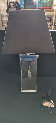A contemporary mirrored glass and chrome-finish table lamp. A contemporary table lamp featuring 