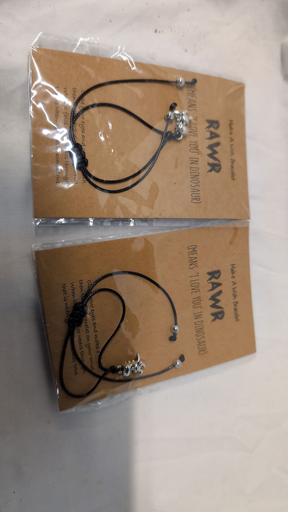 Lot 505: A Pair of Black Cord Make A Wish Bracelets