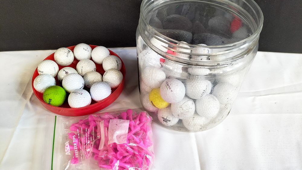 Lot 517: A Collection of Assorted Used Golf Balls and Pink Plastic Tees