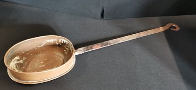 Antique oval copper pan with long hand forged iron handle. A long-handled oval copper pan with a 