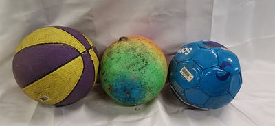 A Trio of Assorted Used Sports Balls. A trio of assorted sports balls comprising a basketball, a 