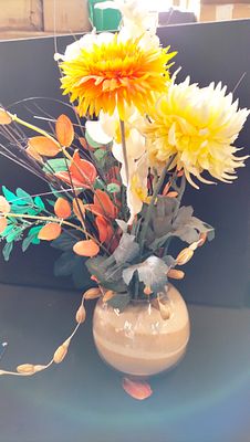 Artificial Floral Arrangement with Yellow and Orange Blooms in a Sand-Filled Glass Vase. This 