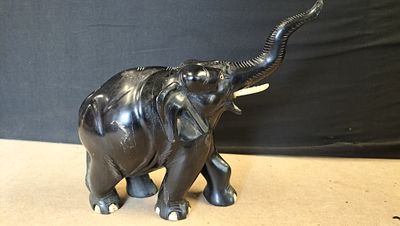 A carved ebony wood elephant figurine with trunk raised. A single black carved ebony wood 