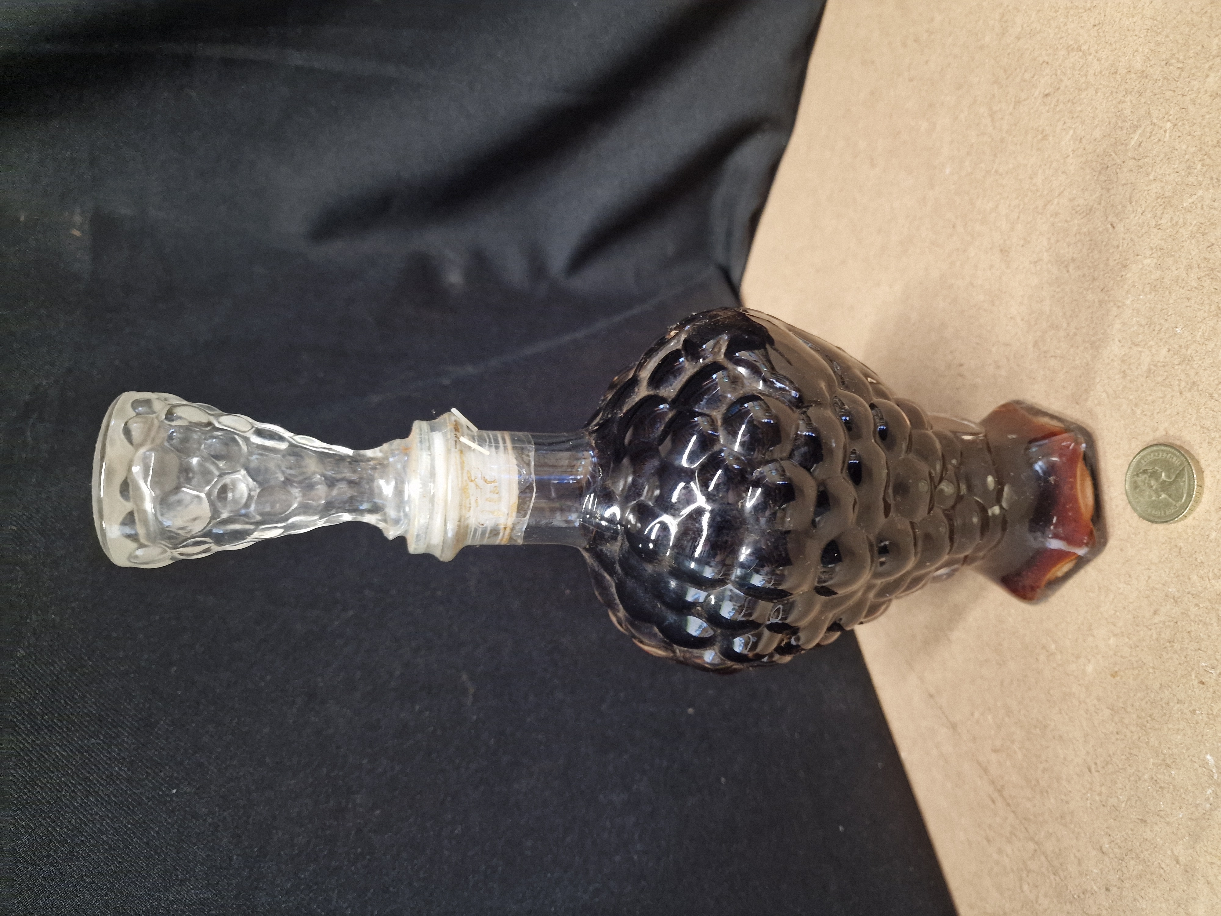 A vintage pressed amber glass grape cluster decanter with clear glass stopper unknown contents. Maybe dessert wine or brandy?