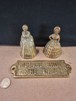Three Vintage Cast Brass Items comprising Two Crinoline Lady Hand Bells and a Gate Plaque