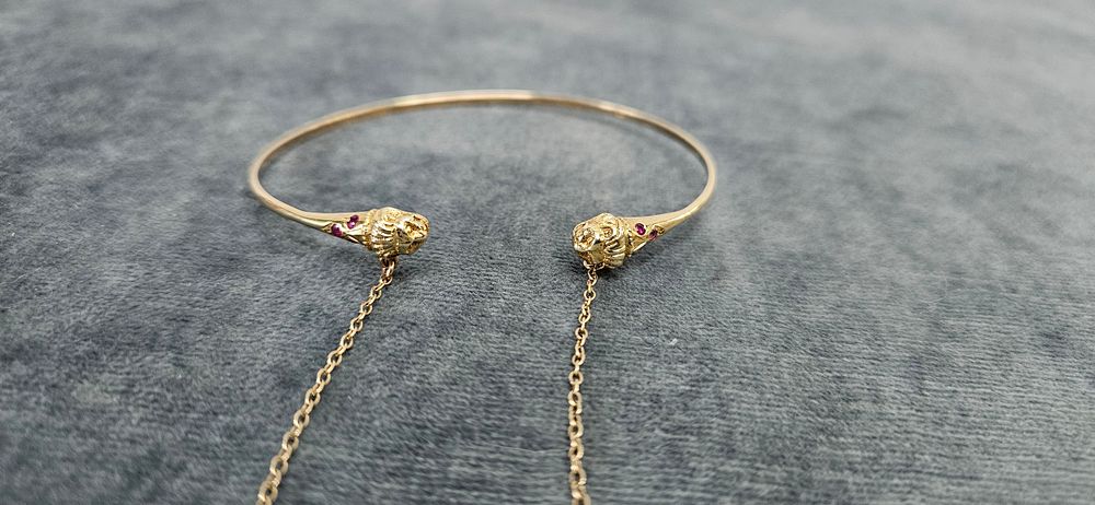 Lot 515: 14ct Yellow gold bangle with lions heads 5.20g...
