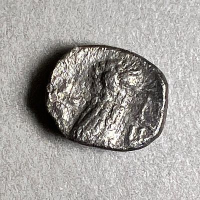 Yehud, 4th century BCE. Silver obol, 0.57 gr; 8.2 mm in diam. Obv: Worn out head of Athena. 
