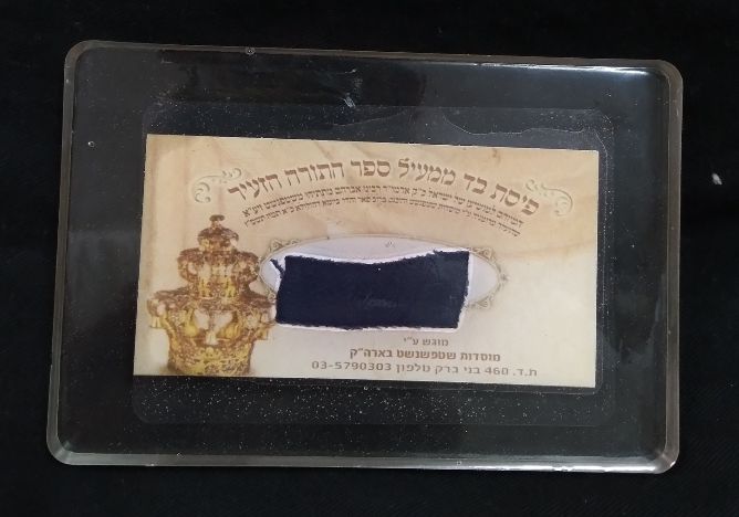 פיסת בד ממעיל ספר התורה הזעיר המיוחס למושיען של ישראל האדמו"ר רבי אברהם מתתיהו משטפנשט, שהועלה 