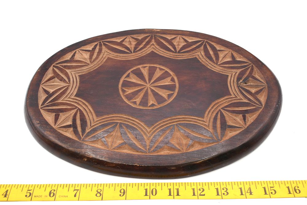 Hand Carved Oval Wooden Plaque or Trivet. A dark brown oval wooden plaque or trivet with carved 
