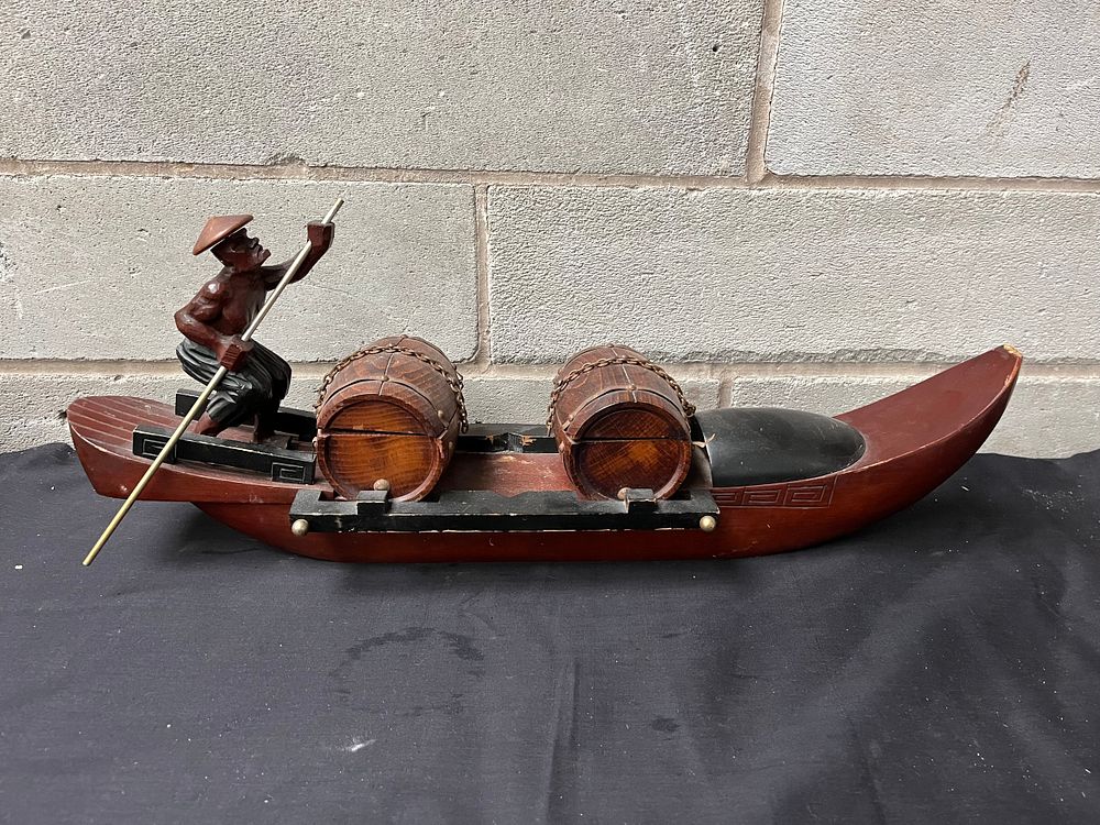 Lot 209: Carved Man On Boat 22" x 9".