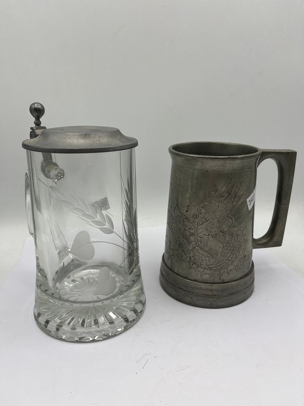 Lot 445: A German Blown Etched Glass Beer Stein and a Commemorative Engraved Pewter Tankard