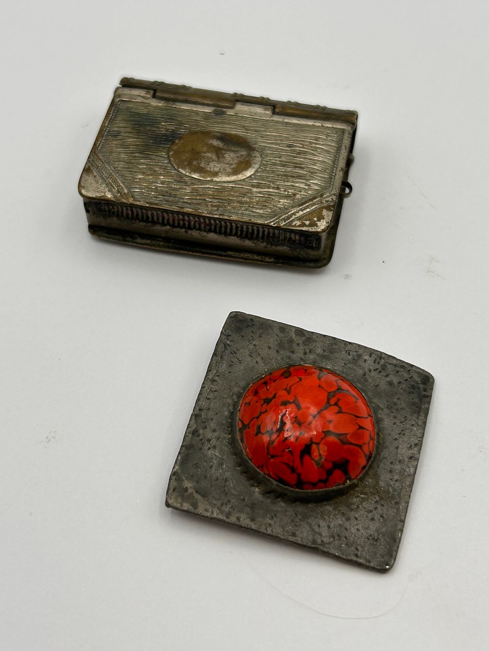 Lot 581: An Embossed Metal Compact and a Cabochon Brooch