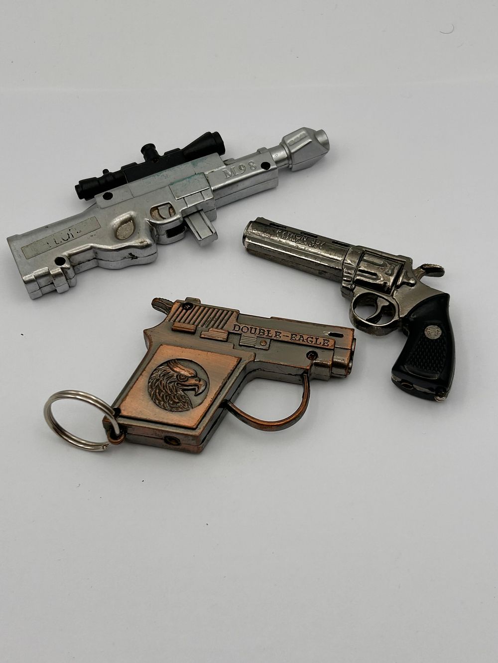 Lot 197: Three Miniature Cast Metal Novelty Gun-Shaped Lighters and Keychains