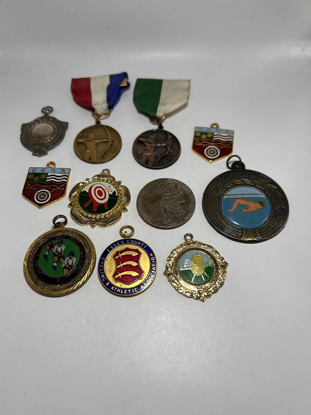 Lot 298: A Collection of 11 Vintage British Sporting Medals and Badges, including Essex County examples