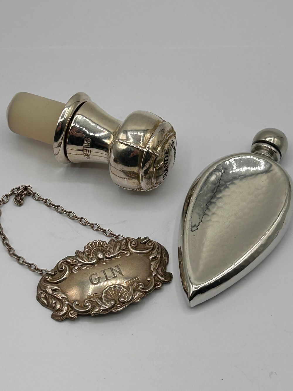 Lot 326: A Group of Three Sterling Silver and Metal Barware Items, including a Sterling Silver Gin Decanter Label