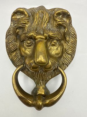 A 6-Inch Brass Lion Head Door Knocker. A cast metal door knocker, featuring a stylized lion's 