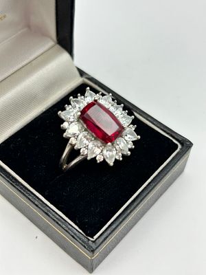 A silver emerald cut red stone and clear stone cluster cocktail ring