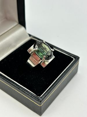 A modernist silver cocktail ring set with a large oval-cut green gemstone