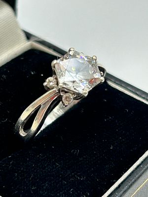 A silver solitaire ring featuring a rectangular-cut clear stone and split-shank shoulders