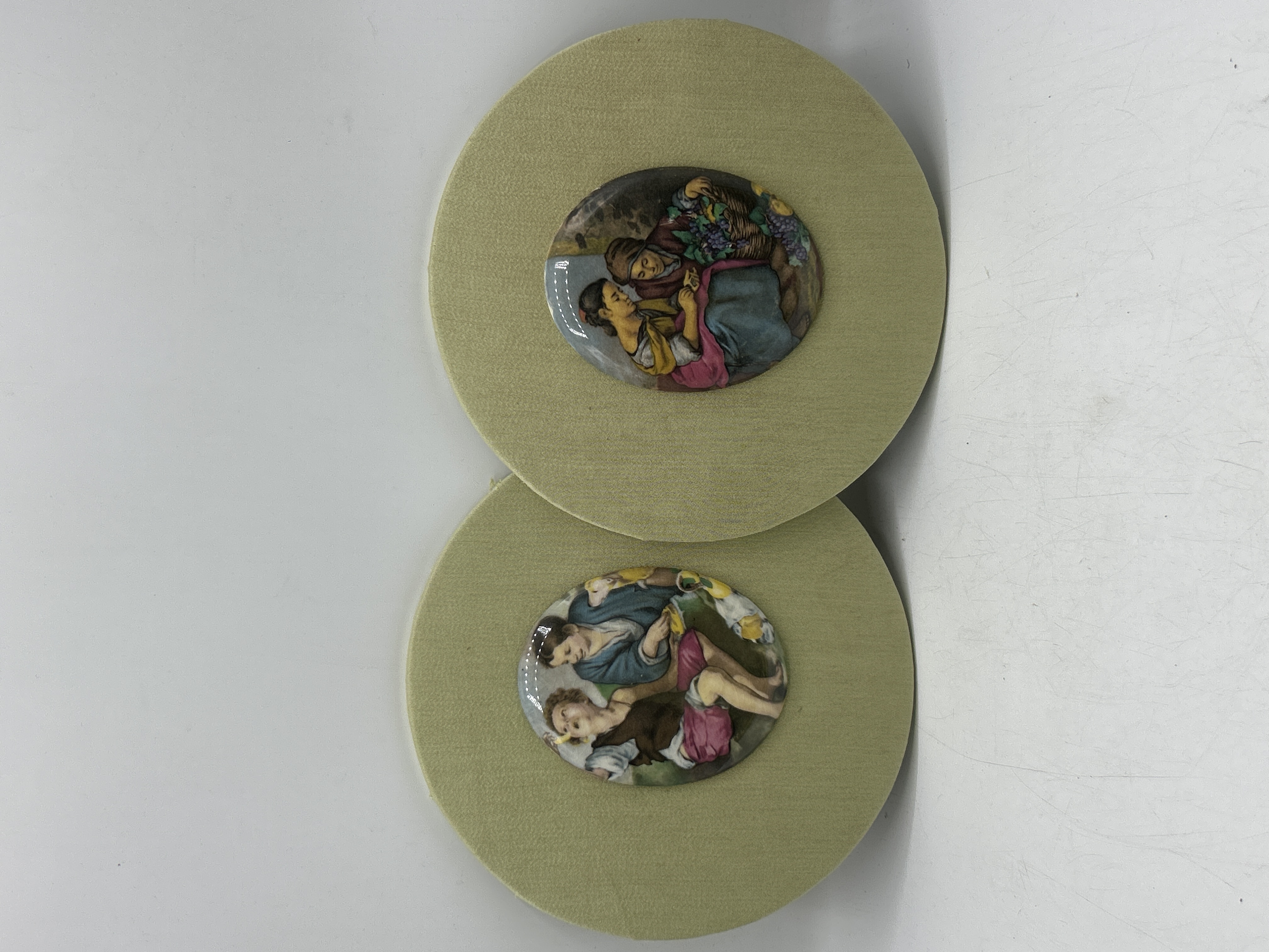 A Pair of Circular Fabric-Mounted Porcelain Wall Plaques with Pastoral Scenes
