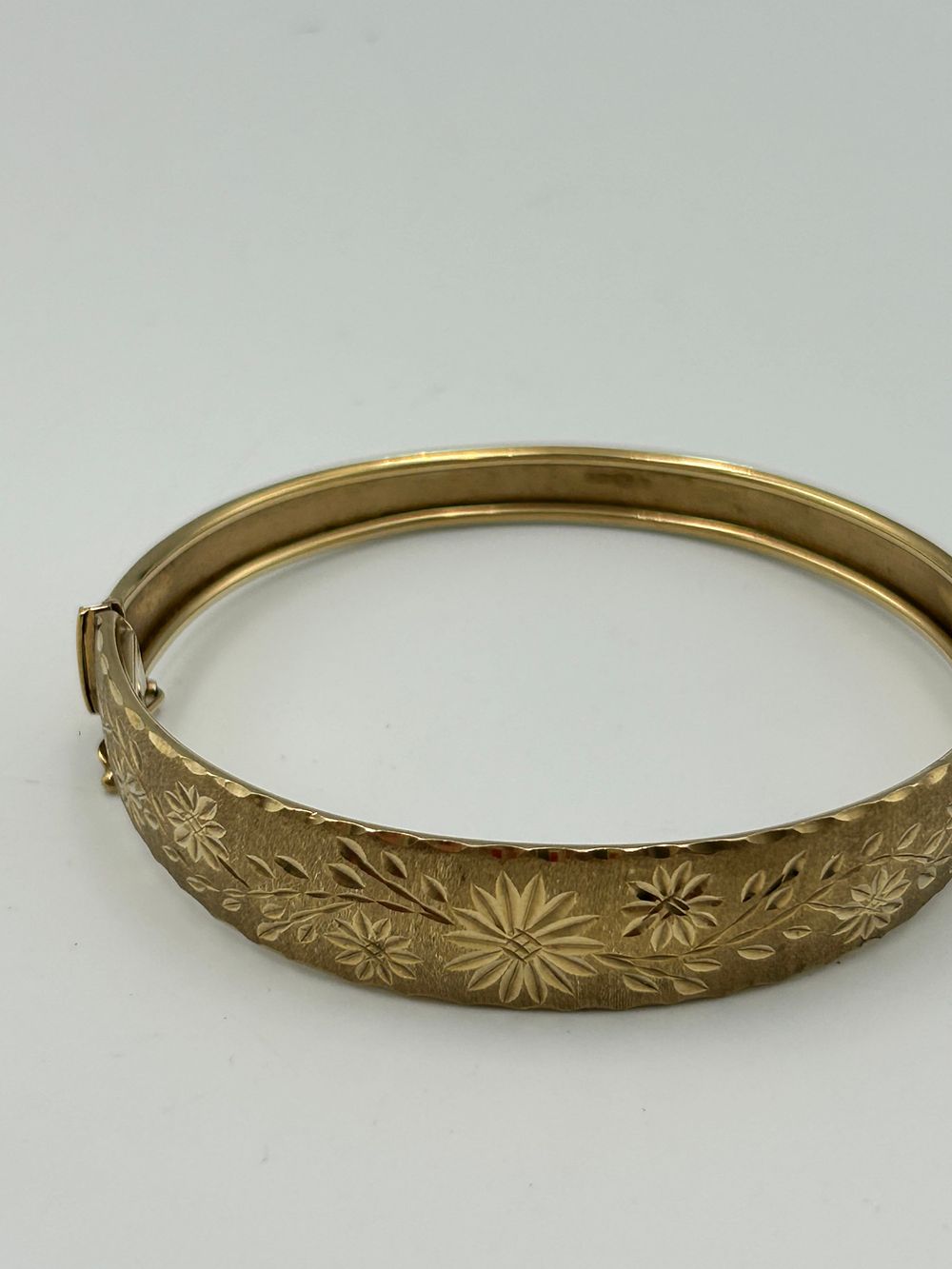 Lot 833: An Italian 9 Carat Gold Engraved Floral Hinged Bangle, 9.39g