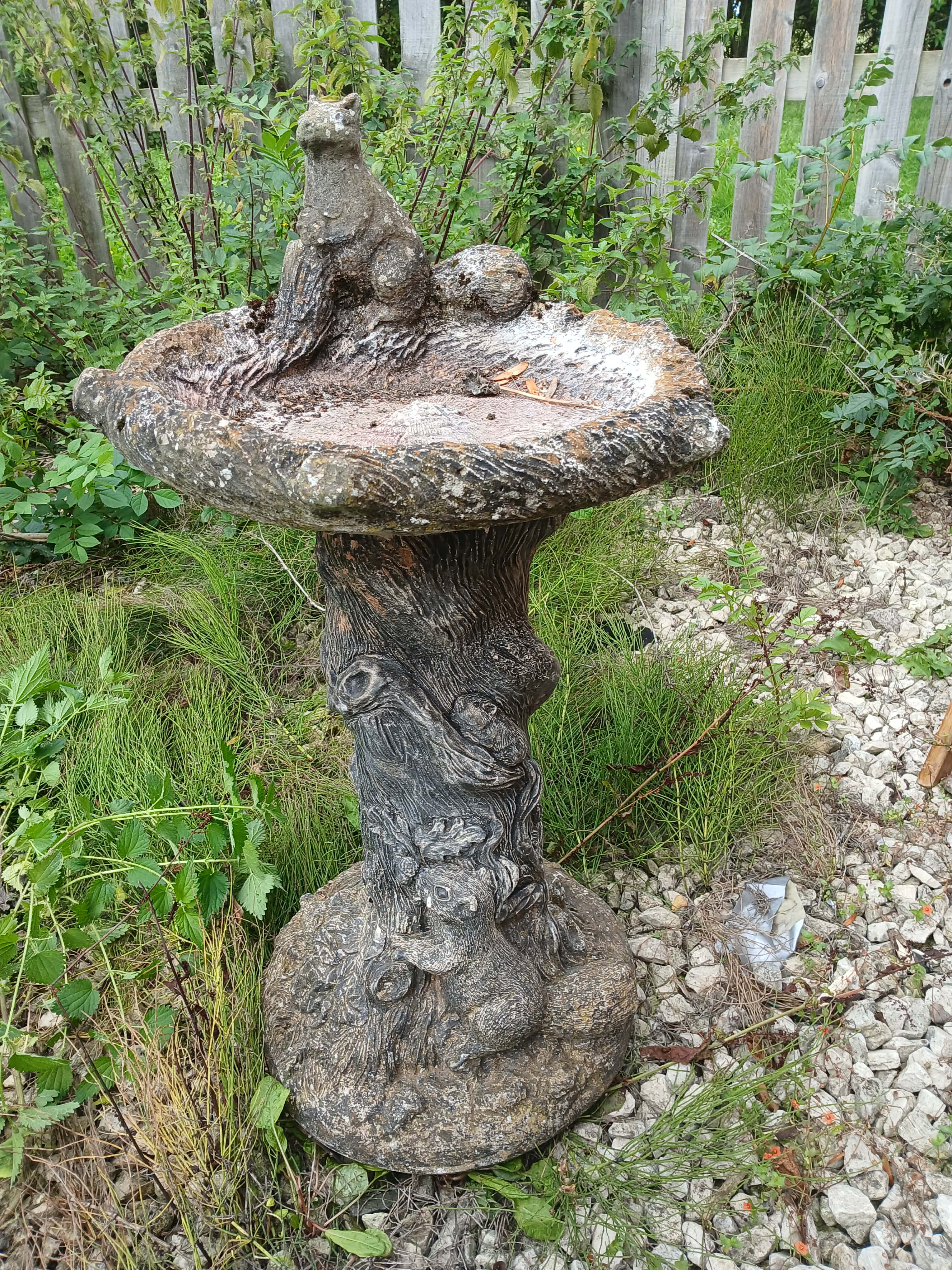 A Rustic Cast Stone Two-Piece Bird Bath With Squirrel and Bird Motif