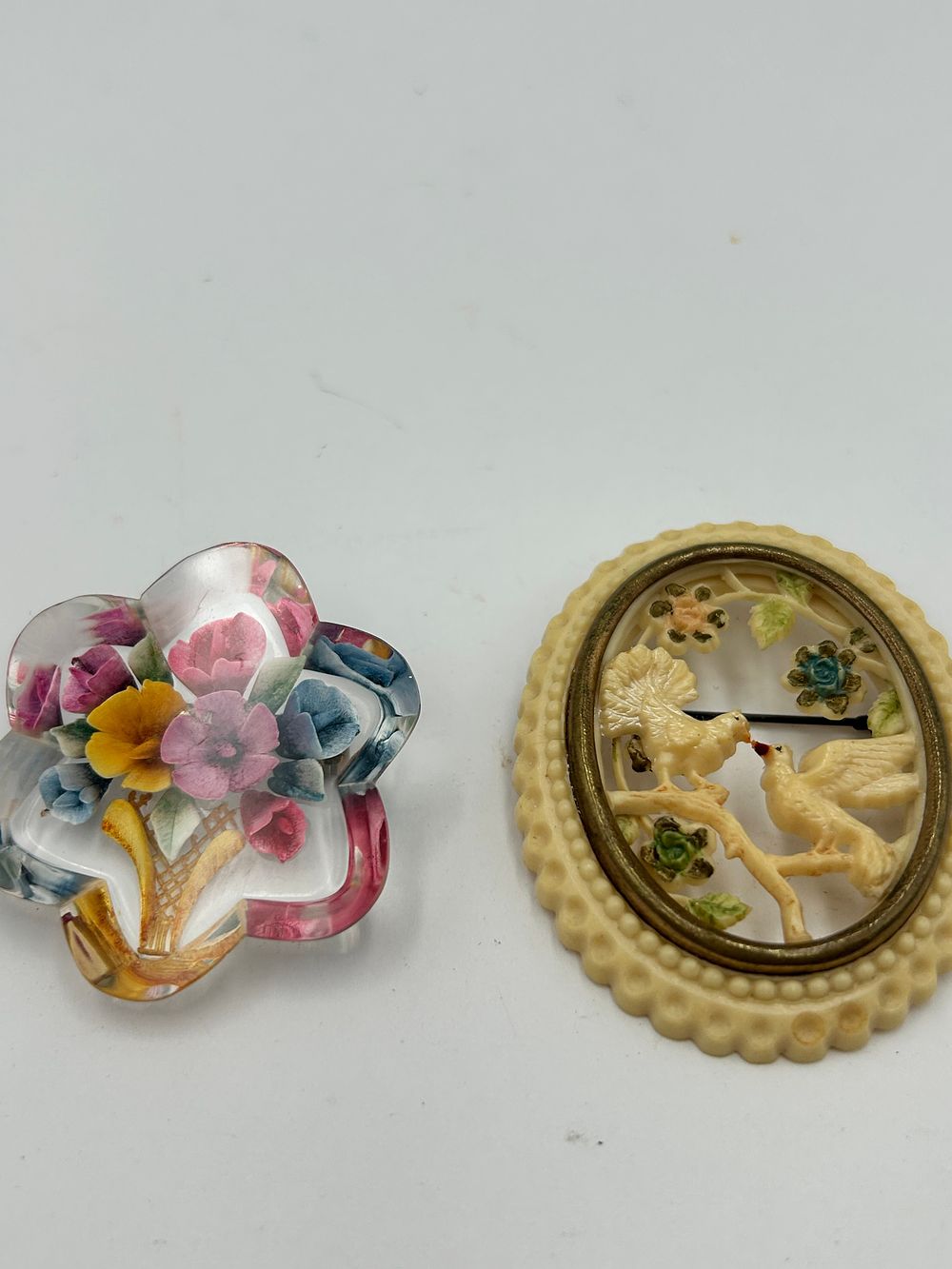 Lot 98: Two Early Plastic Carved Bird and Reverse-Carved Lucite Flower Basket Brooches
