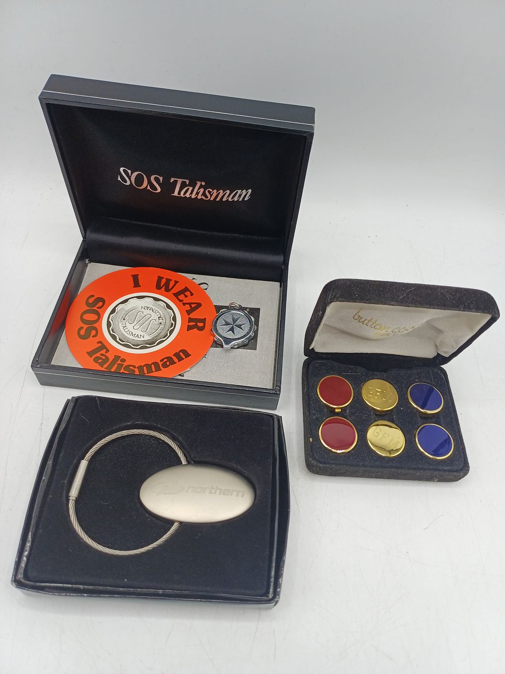 Lot 549: An Assortment of SOS Talisman, GFM Button Covers, and Northern? Keychain